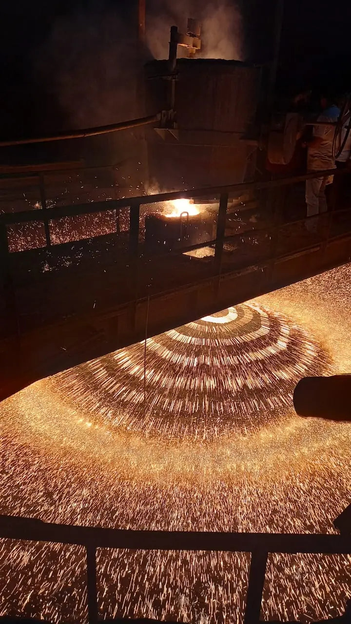 Molten steel being granulated into shot, sparks fanning out across the plant floor